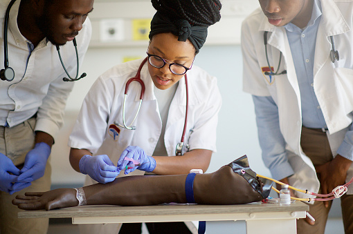 Students practising IV injection on a Phlebotomy Venipuncture Practise Arm with a medical instructor teaching the correct way in a University Hospital in Cape Town South Africa